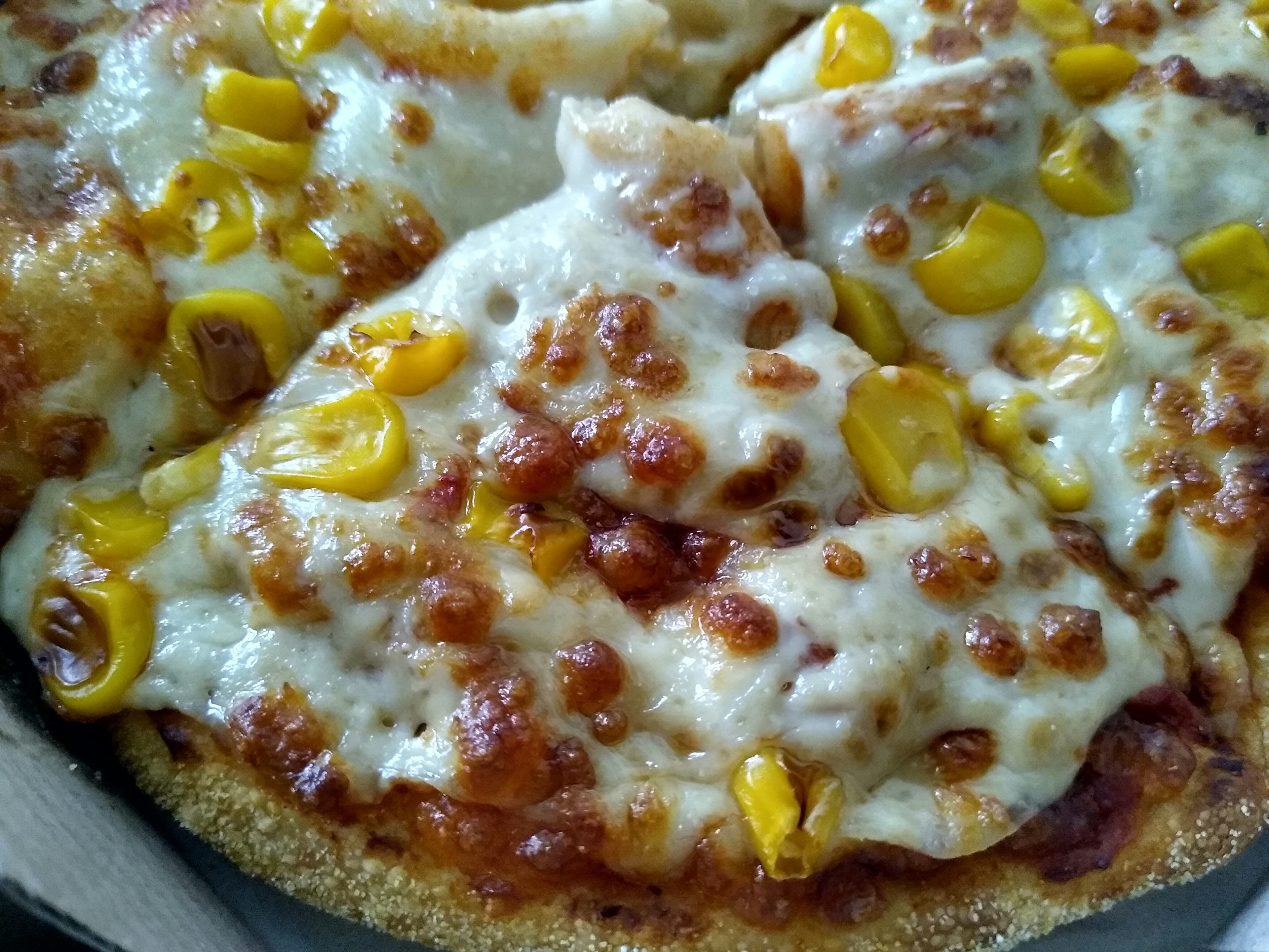 Corn pizza with sweet corn kernels on creamy white sauce and mozzarella
